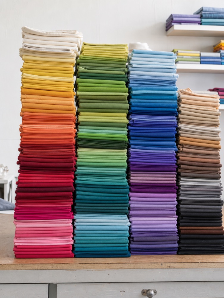 Stacked folds of Cotton Couture fabric swatches in many solid colours.